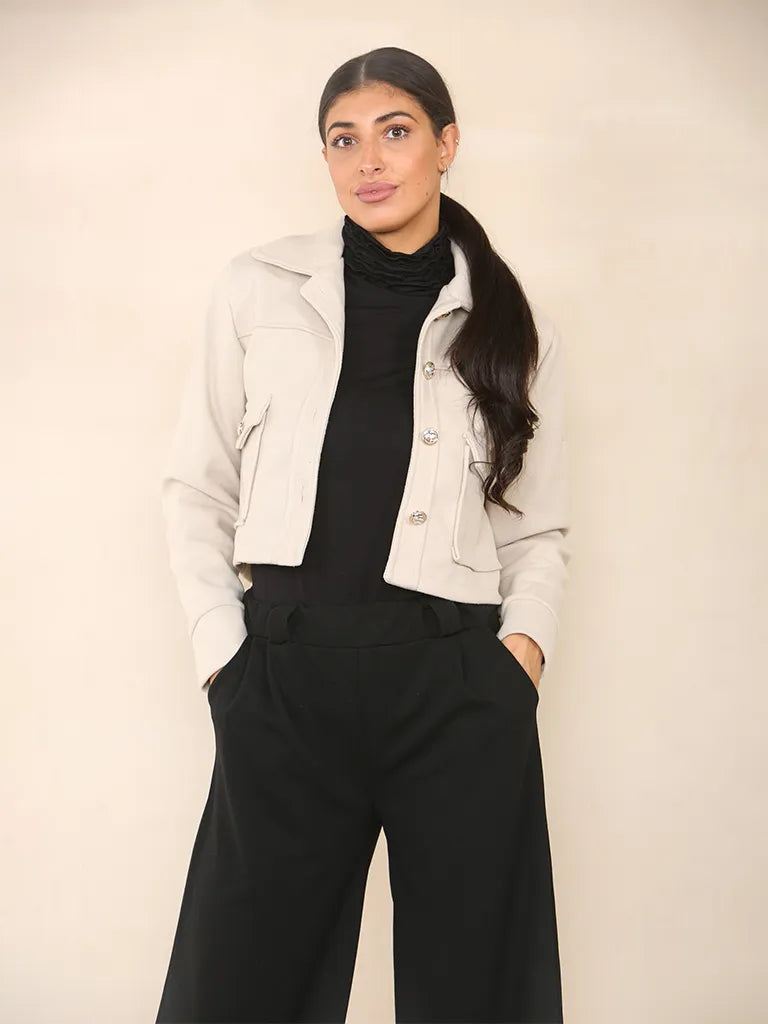 model wearing a cream collar crop jacket that buttons up.  Long sleeve jacket with two front pockets.  Selling jacket at wholesale fro retailers looking for bulk buys